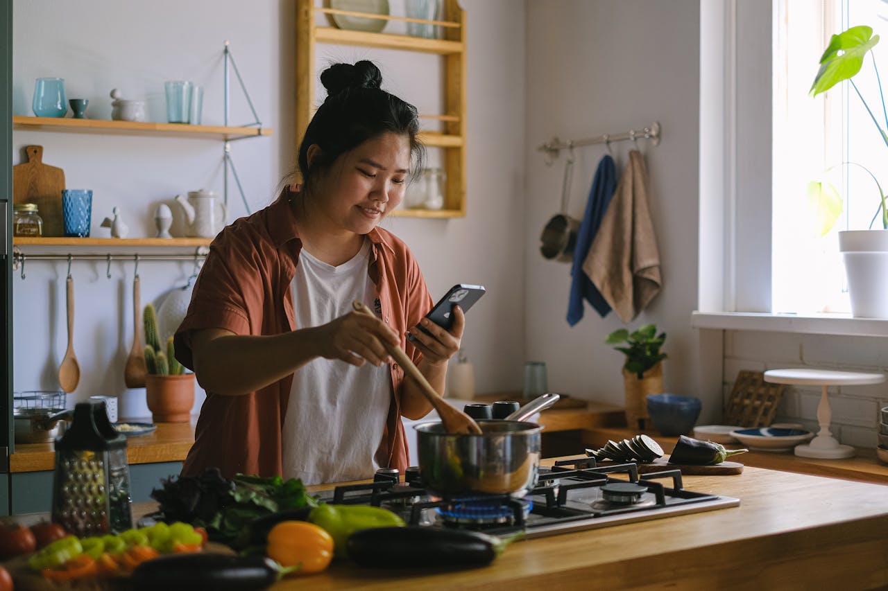 woman on phone while cooking pexels