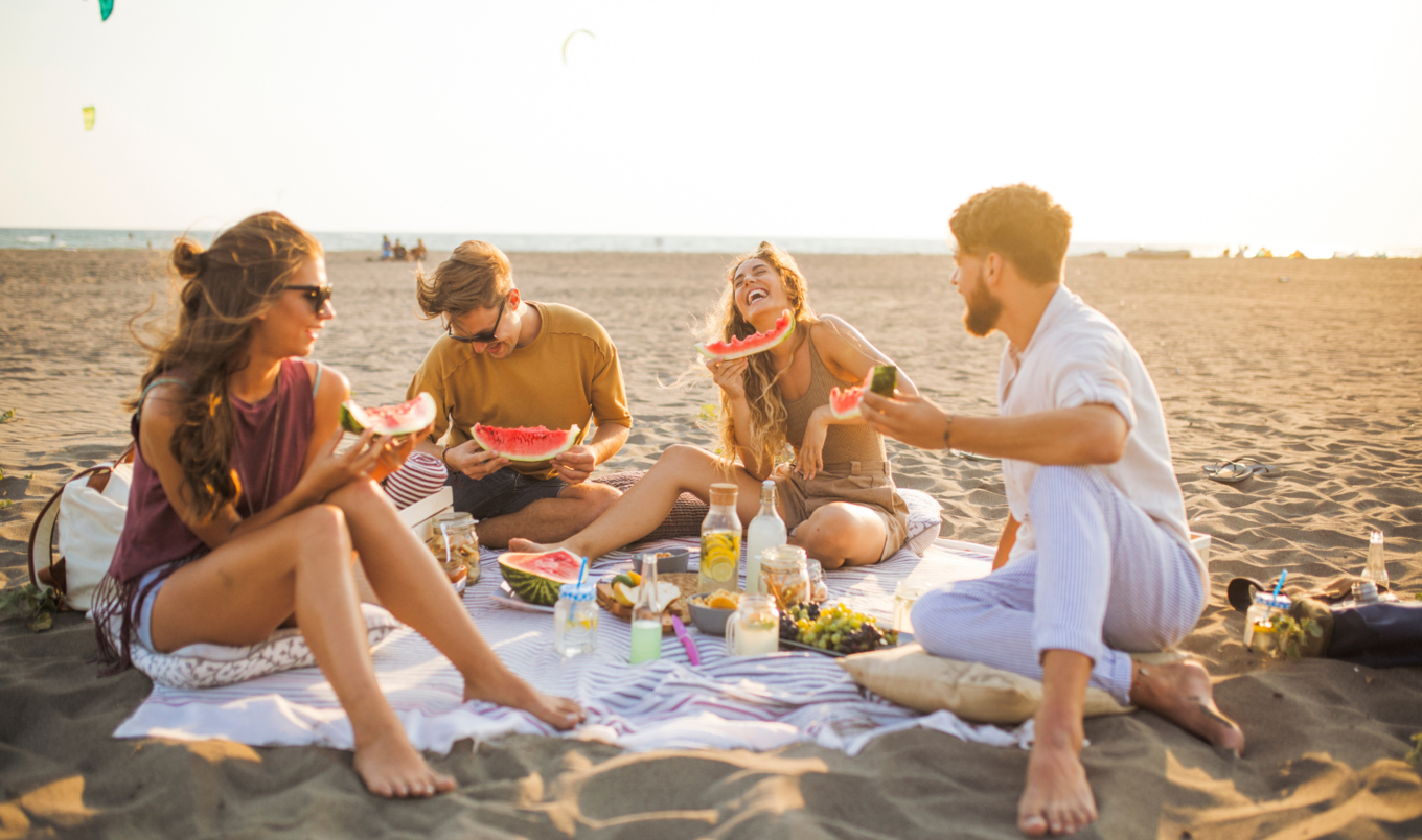 people eating watermelon at the beach